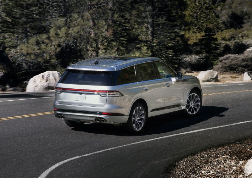 A 2023 Lincoln Aviator® Grand Touring model is shown being driven on a tight turn of a mountain road | Carman Lincoln in New Castle DE